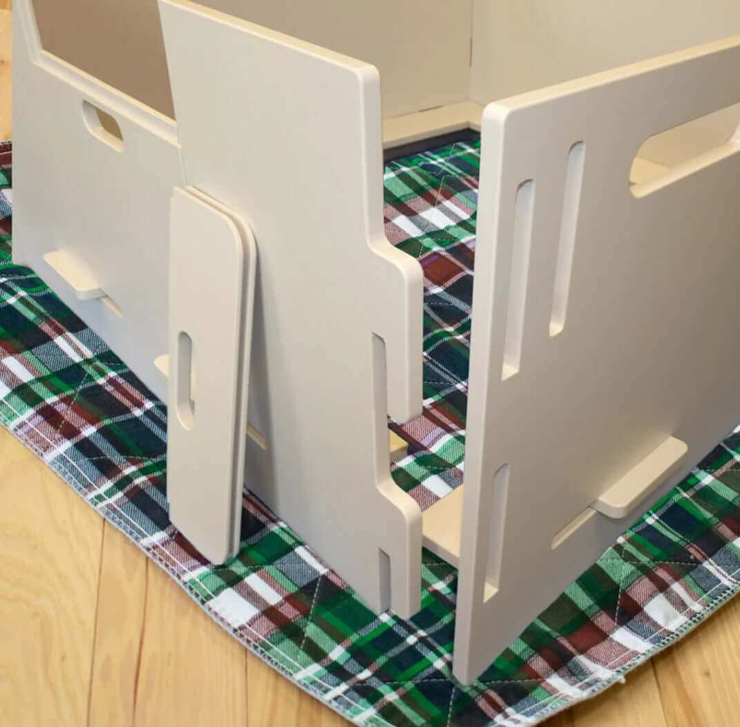 A modular whelping box with interlocking sides, designed for easy assembly and disassembly. It provides a secure and comfortable space for a dog to give birth and care for her puppies.