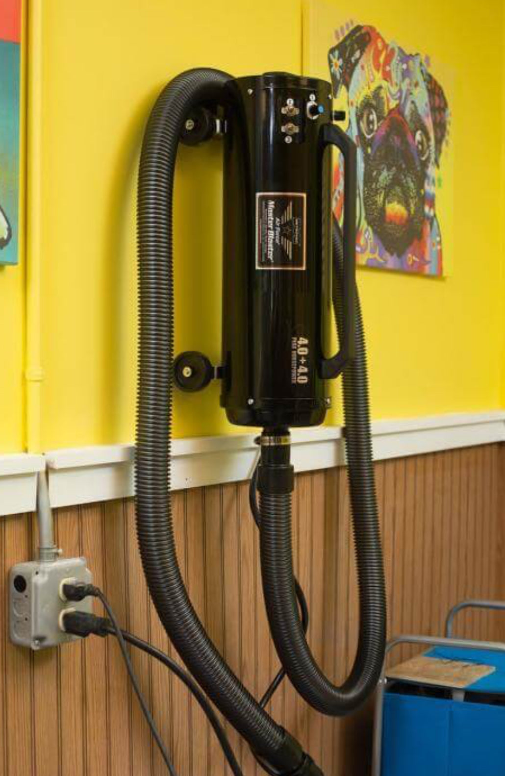 Metrovac Air Force Master Blaster high-velocity pet dryer with dual 4.0 HP motors, 58,500 FPM airflow, and no heating element for safe, efficient grooming hanging on the wall