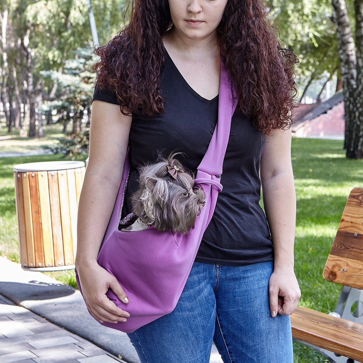 A girl wearing a Comfortable pet slings with her dog in it great for for carrying small dogs and cats – hands-free, adjustable, and stylish pet carriers